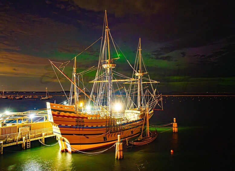 A large sailing ship docked at a pier with a colorful aurora display in the background. 3