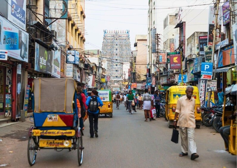 Una calle concurrida con rickshaws, peatones y diversas tiendas. 5