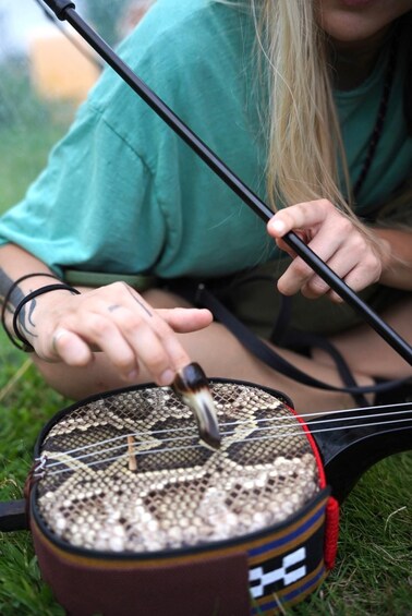 Eine Person spielt draußen ein Saiteninstrument. 2