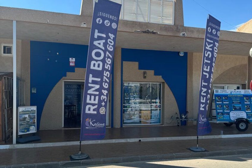 A building with blue doors and a sign for 'RENT BOAT' with a phone number. 2