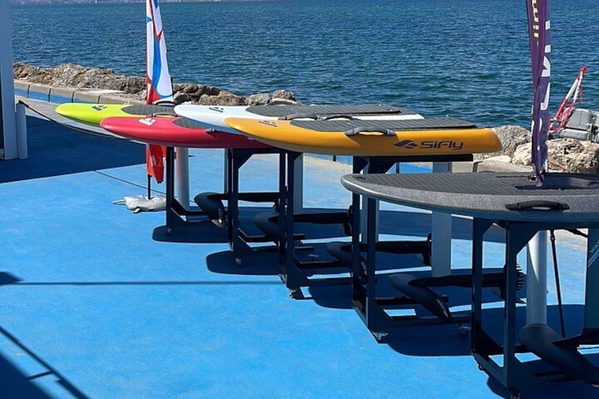 A row of surfboards on a blue deck by the water. 3