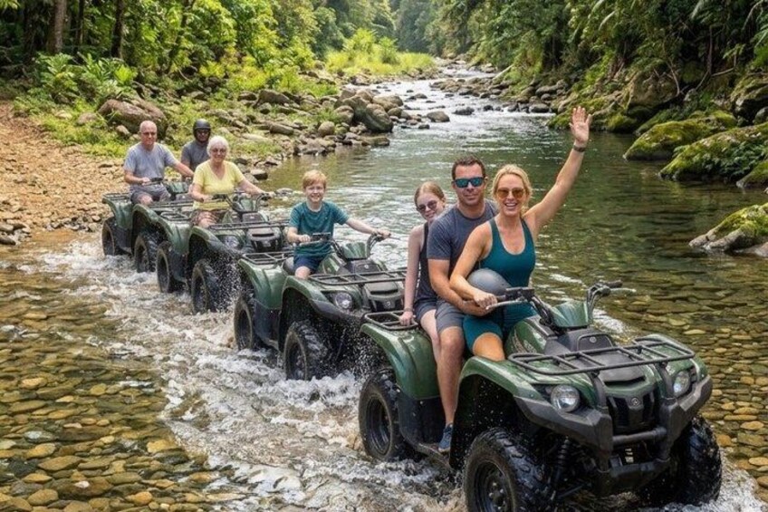 A group of people riding ATVs along a river surrounded by greenery. 3