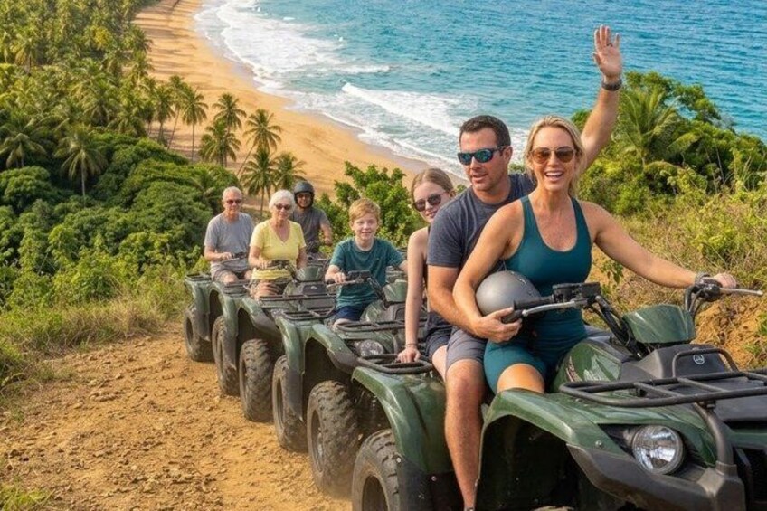 A group of people on ATVs on a dirt path with a beach and ocean in the background. 4