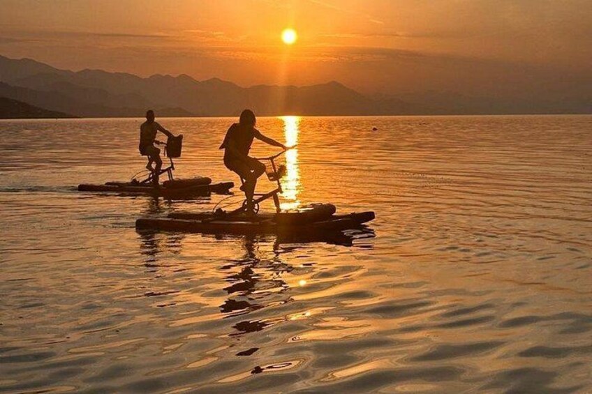 Two people riding paddleboards on a calm body of water during sunset. 4