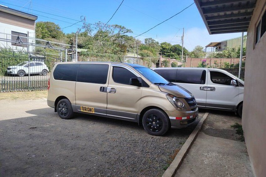 A beige van parked in a driveway with a 'TURISMO' sign on the side. 5