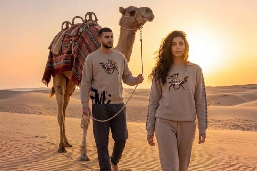 Two people walking with a camel in a desert landscape. 2
