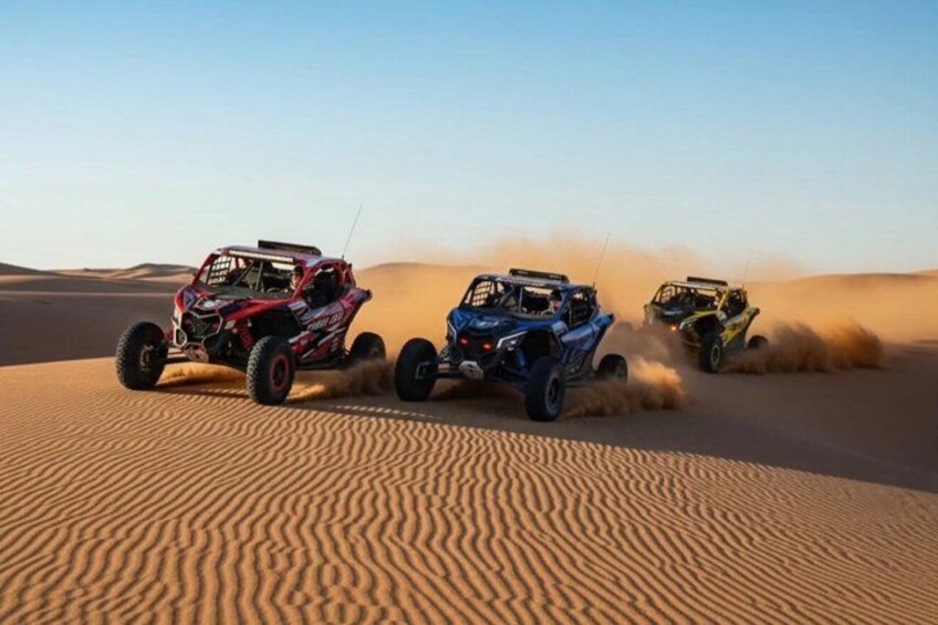 Three off-road vehicles racing on a desert sand dune. 3