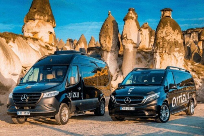Two Mercedes-Benz vans parked in a rocky landscape with unique rock formations in the background. 4