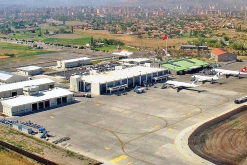 An airport with multiple hangars, a control tower, and parked aircraft. 5