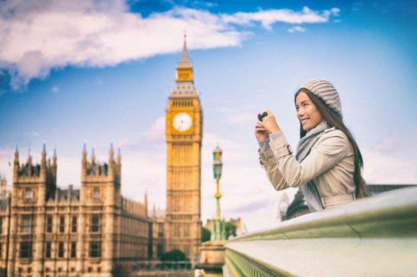 A person taking a photo of the Big Ben clock tower with the Houses of Parliament in the background. 2