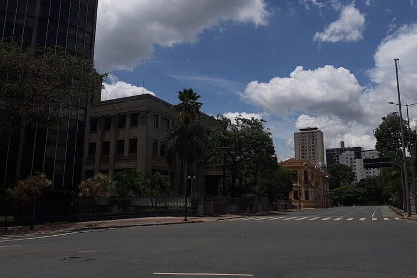 A city street with buildings, trees, and a clear sky. 1