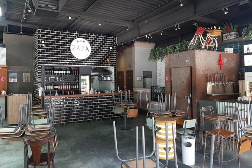 A restaurant interior with a brick wall, bar counter, and seating area. 3