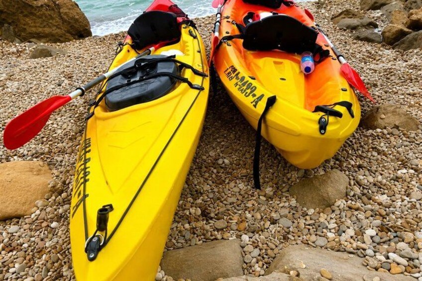 Two kayaks on a pebbled beach with rocks and the ocean in the background. 5