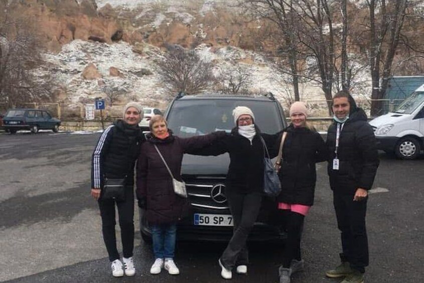 Four people standing in front of a black car with a license plate number 50 SP 7. 2