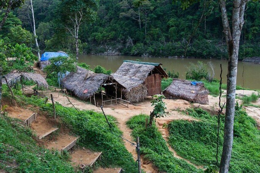 A rural village with thatched-roof huts near a river. 3