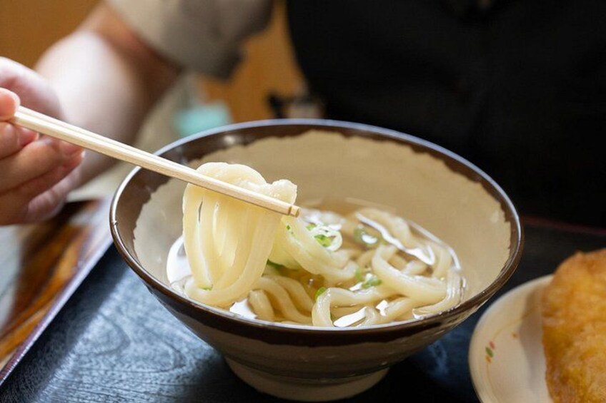 A bowl of ramen noodles being lifted with chopsticks. 5