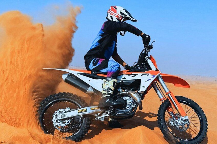 A person riding a dirt bike on a sandy terrain. 5