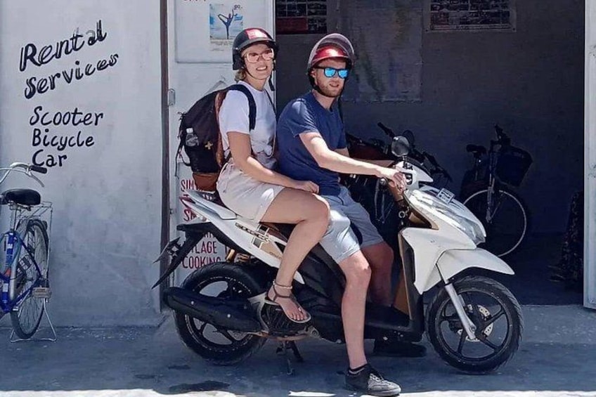 Two people on a scooter, a wall with rental services text, and a bicycle. 4