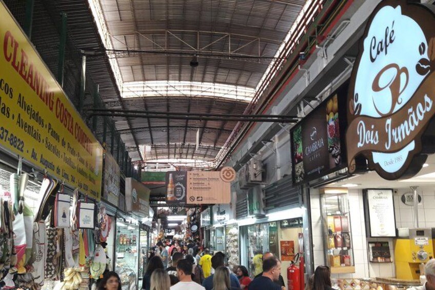 A busy indoor market with various shops and signs. 3