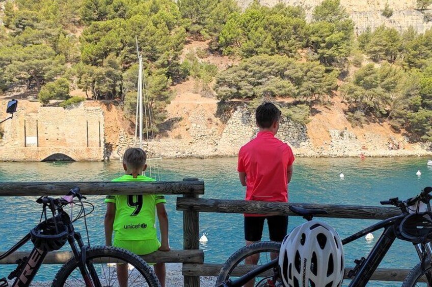 A coastal scene with a wooden railing, a sailboat, and bicycles. 5