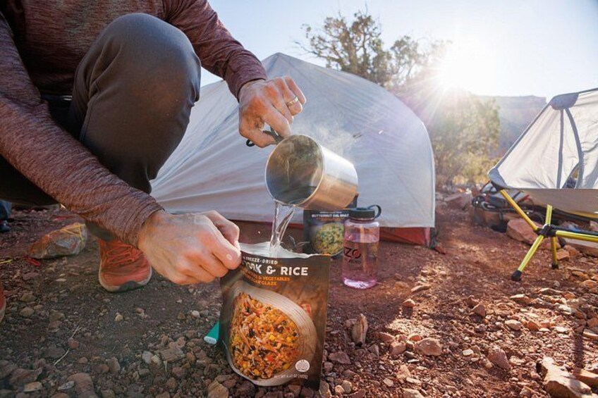 A person cooking rice outdoors with a portable stove. 4