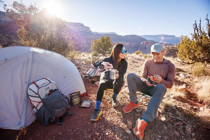 A tent, a backpack, and a person holding a device in a desert landscape. 5