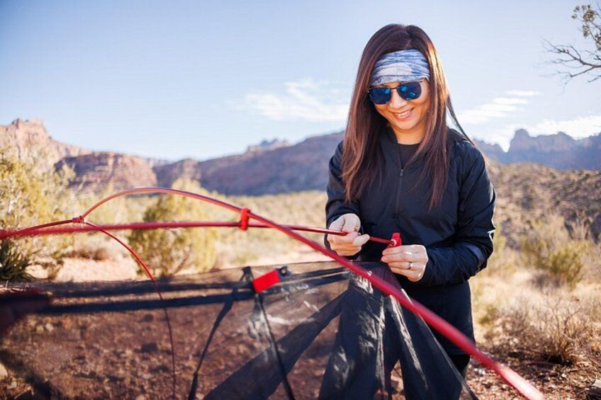 A person holding a red object, possibly a tool, in a desert landscape with mountains in the background. 3