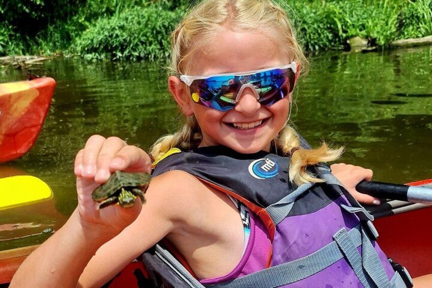 A person in a kayak holding a frog. 4