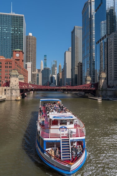 A riverboat with passengers, a bridge, and a city skyline with tall buildings. 4