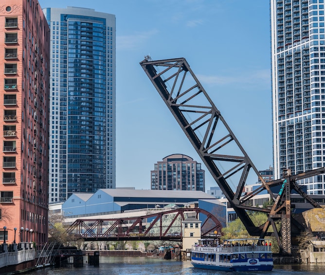 A river with a bridge, a boat, and tall buildings. 3