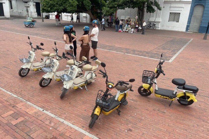 A paved area with several scooters parked. 3