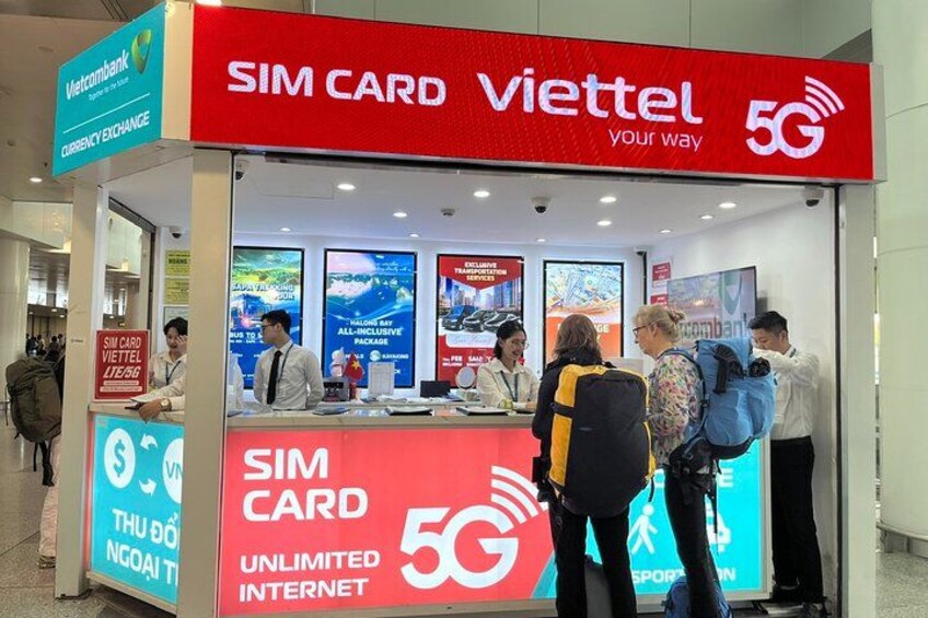 A SIM CARD Viettel kiosk with a 5G logo, a currency exchange sign, and a sign for unlimited internet. 5