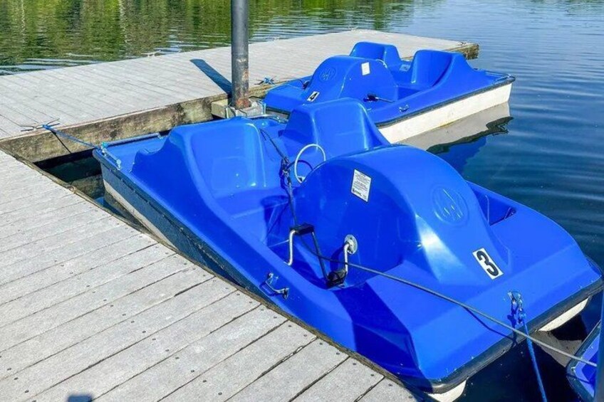 A blue boat docked at a wooden pier with calm water in the background. 2