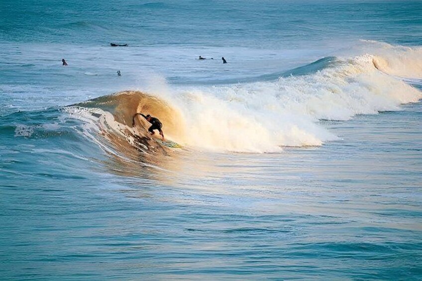 A surfer riding a wave in the ocean with other surfers in the background. 2