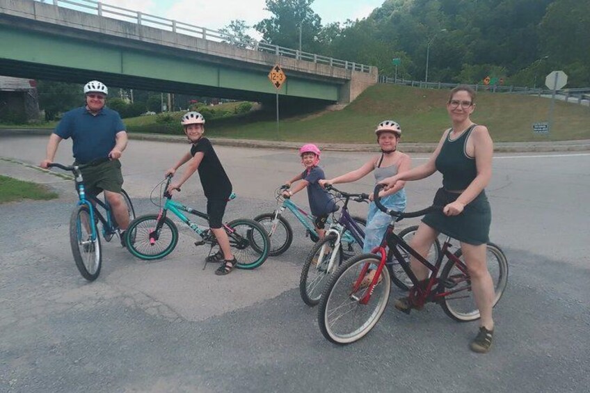 A group of people on bicycles on a road with a bridge in the background. 2