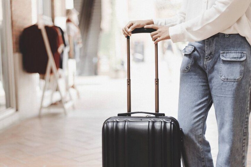 A person pulling a black wheeled suitcase. 2