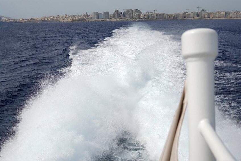 A boat's wake in the ocean with a city skyline in the background. 3