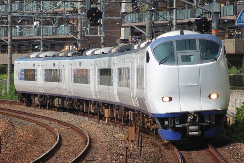 A high-speed train on tracks with overhead electrical lines and a signal light. 1