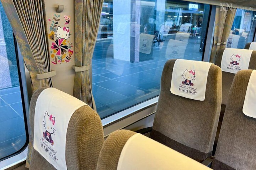 A train interior with Hello Kitty-themed seat covers and curtains. 3