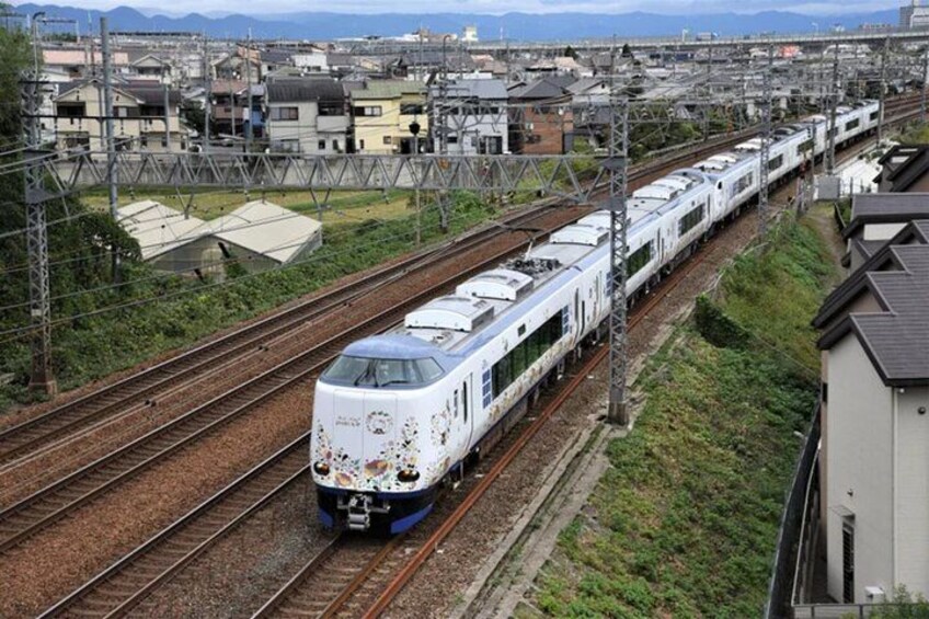 A white train with blue accents traveling on a railway track. 5