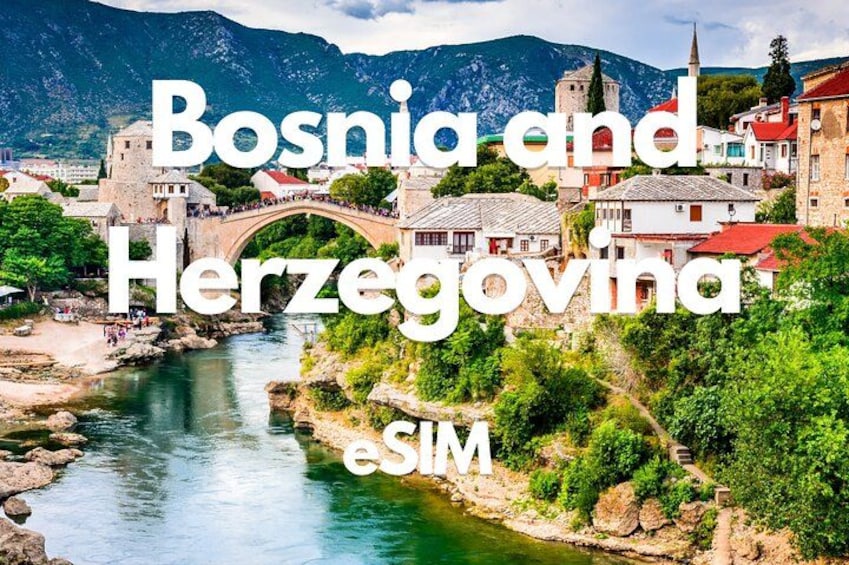 A scenic view of a river with a bridge, historic buildings, and mountains in the background. 1