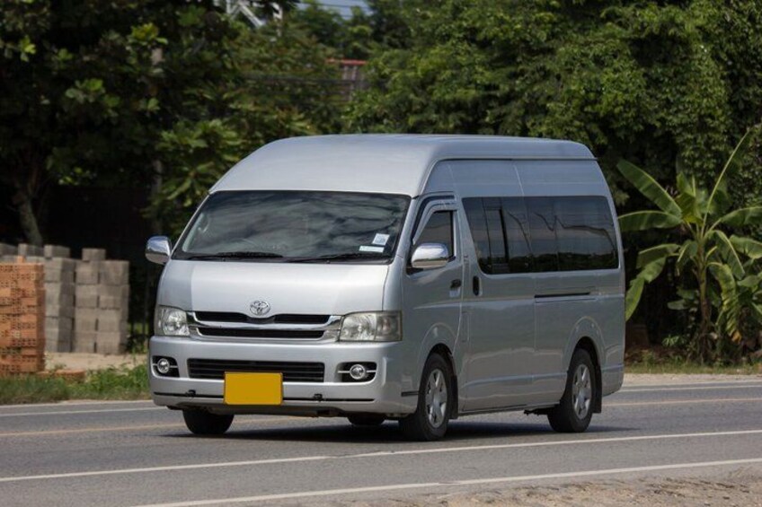 A silver van driving on a road with greenery in the background. 4