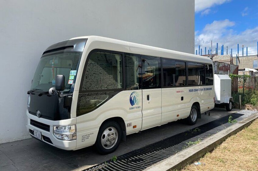 A white bus parked on a concrete surface next to a building. 3