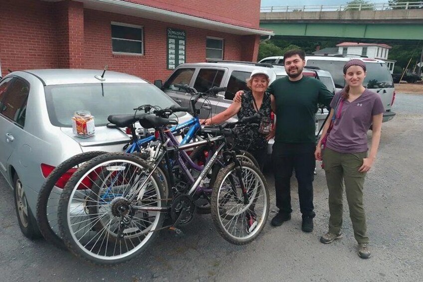 A silver car parked in a lot with a bicycle rack attached to it. 2