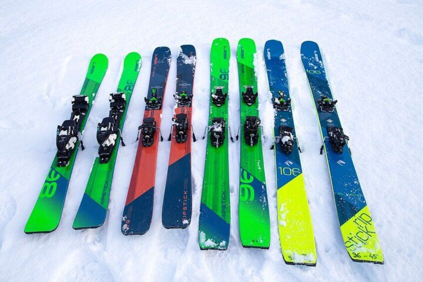 A row of skis with bindings on a snowy surface. 5