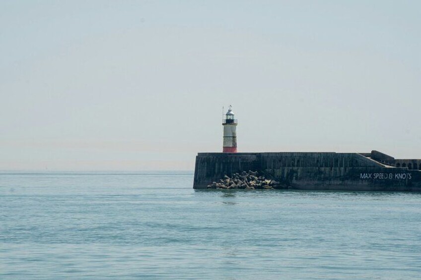 A lighthouse on a pier with calm water. 4
