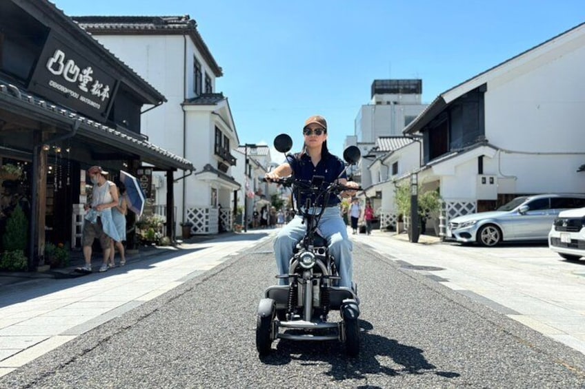 A person riding a motorcycle down a street lined with buildings. 3