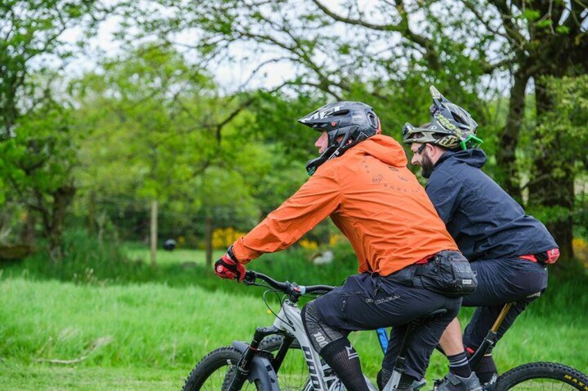Two cyclists on a trail with trees in the background. 4