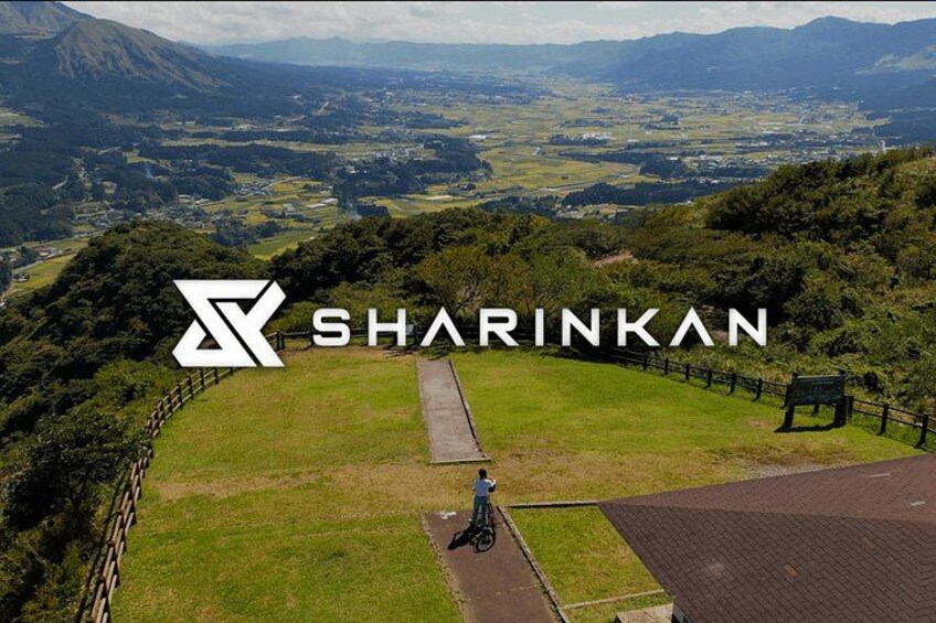 A grassy area with a paved path, a fence, and a sign. 4