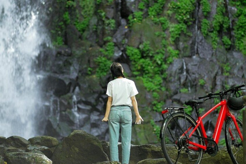 A person standing by a waterfall, a red bicycle, and a rocky landscape. 5